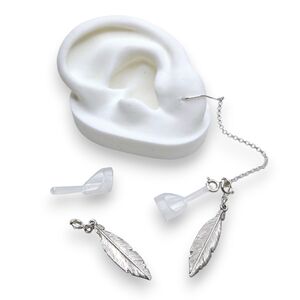 White ear mould next to feather earring in chain which fit to wireless earphones